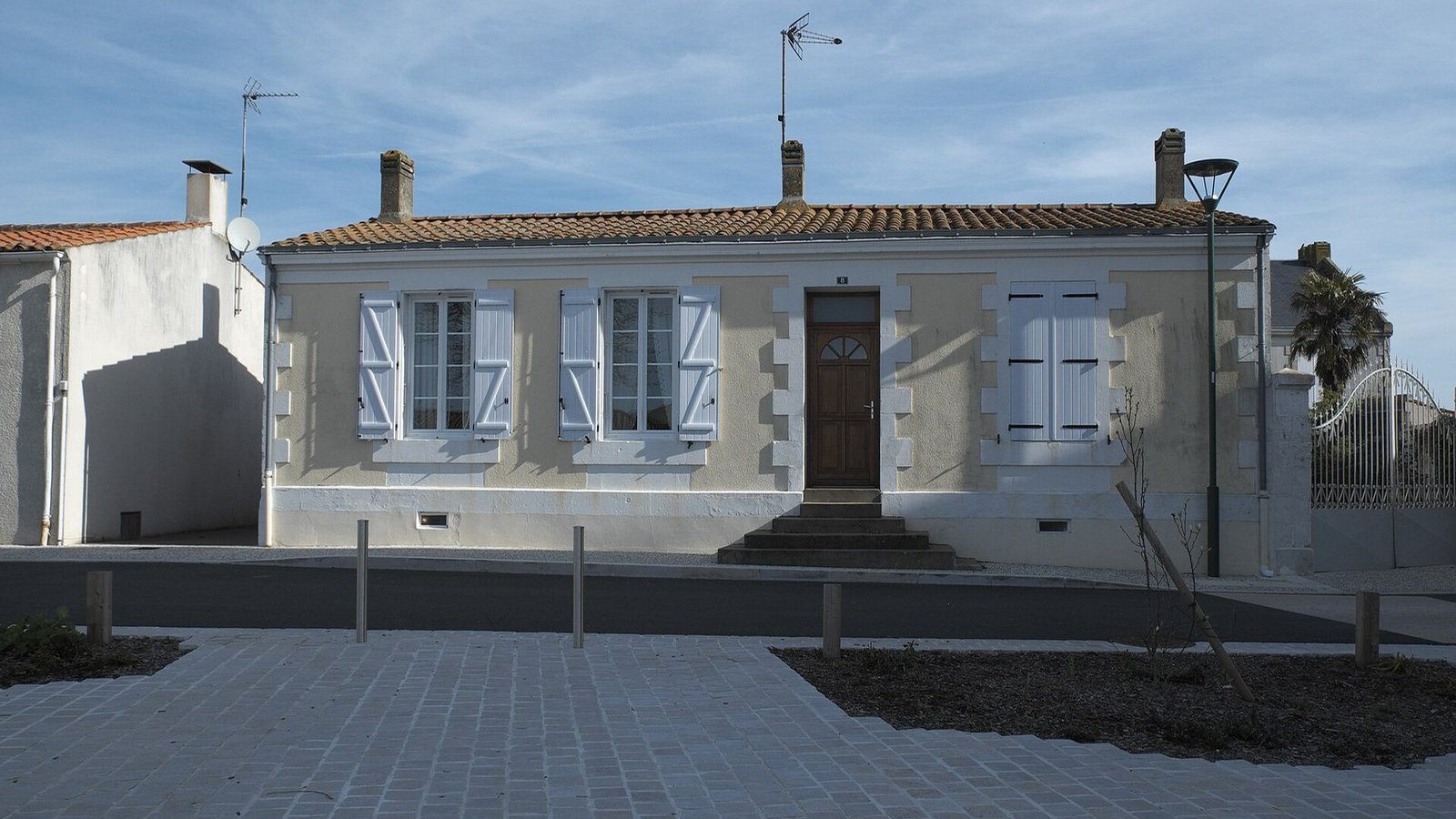 Maison basse vendéenne aux volets blancs, sous un ciel bleu