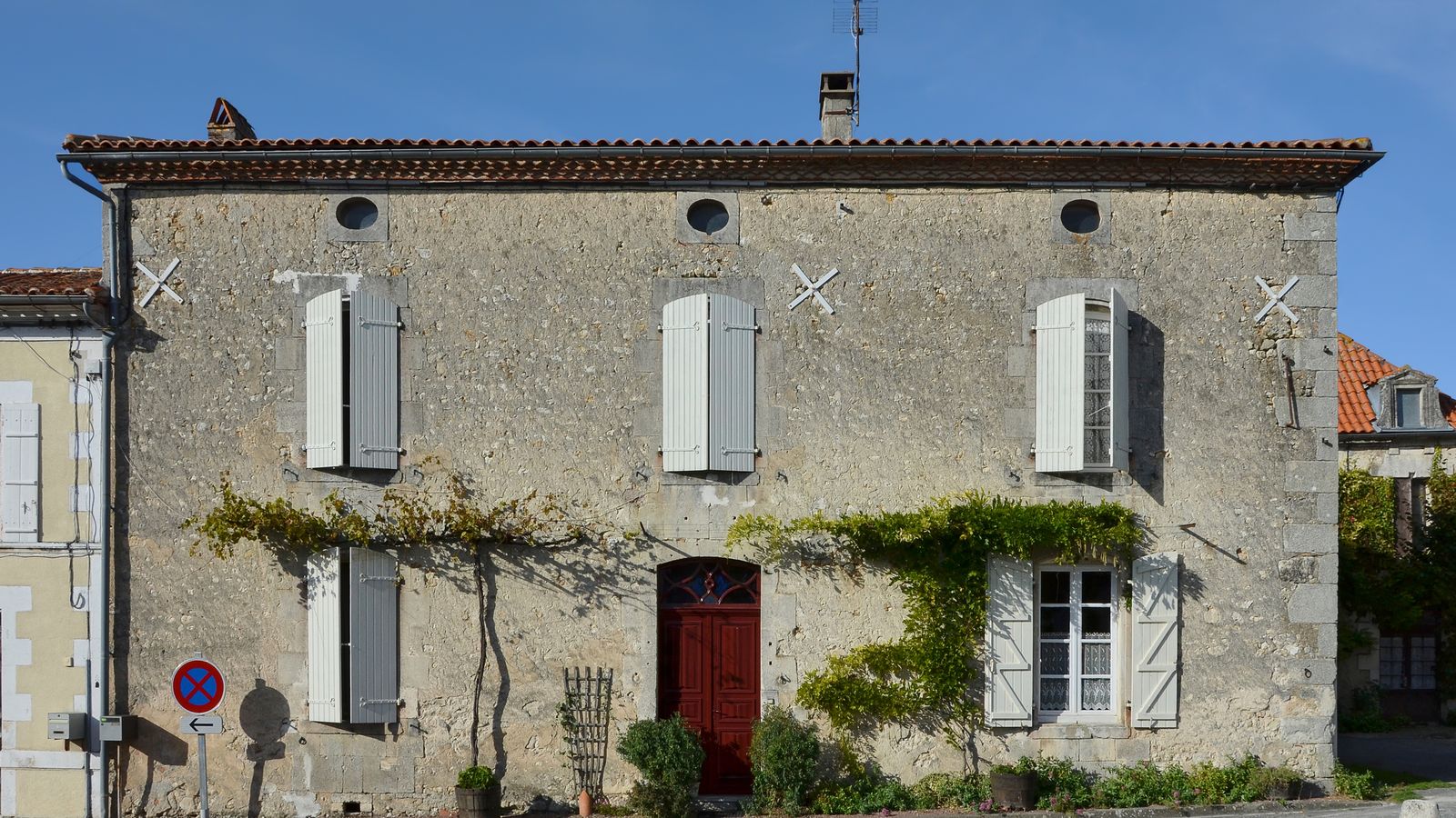 Maison de famille en pierre aux volets clairs, glycine sur la façade