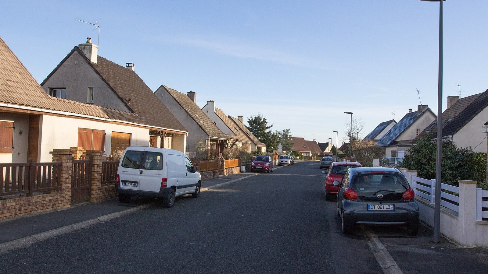 Street of detached houses with small gardens, in the sun
