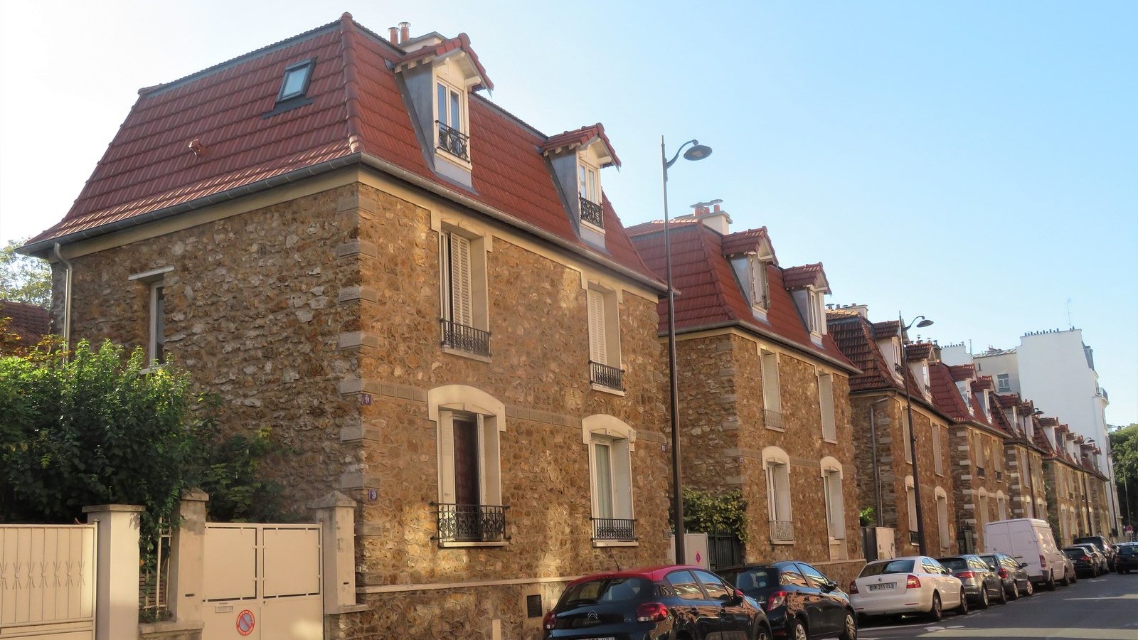 Rangée de maisons en meulière aux toits rouges le long d'une rue ensoleillée