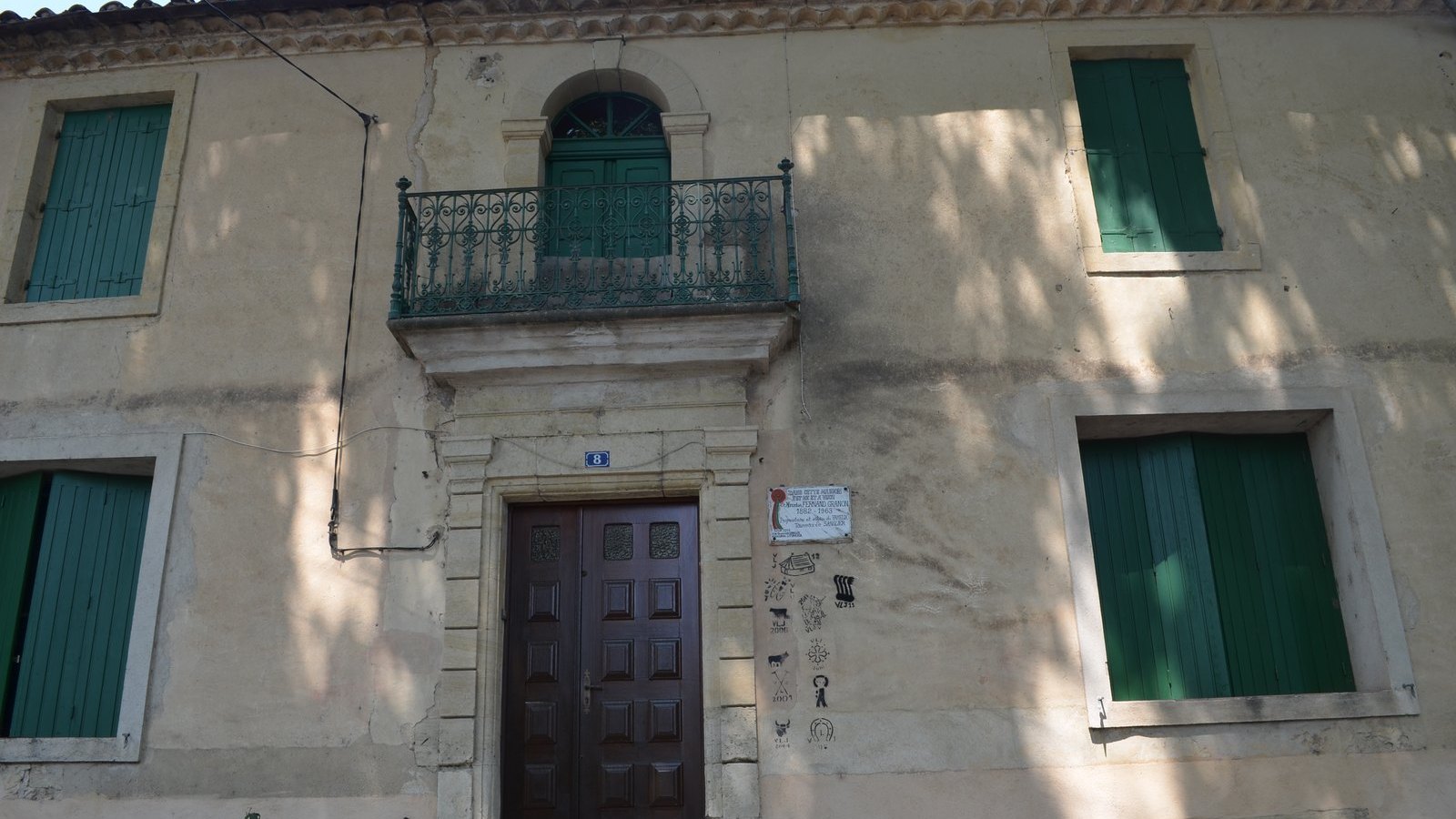 Façade de maison ancienne aux volets verts fermés