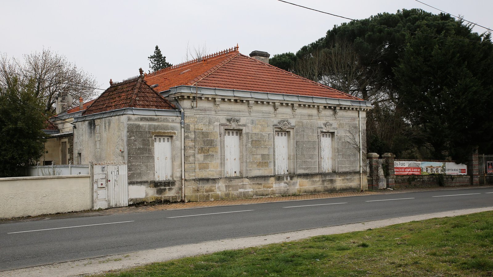 Gironde stone house with closed shutters and a red tile roof, by a road